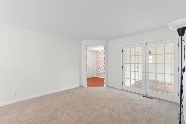 carpeted empty room featuring baseboards, visible vents, and french doors