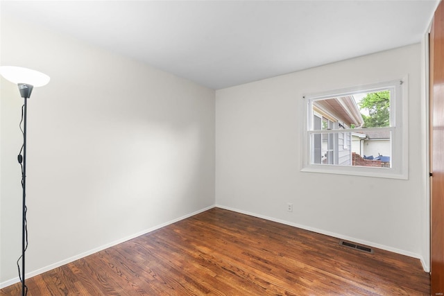 unfurnished room featuring visible vents, baseboards, and dark wood-type flooring