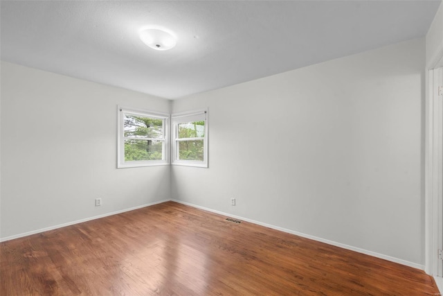 unfurnished room featuring baseboards, visible vents, and wood finished floors