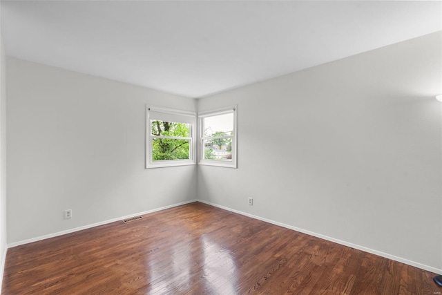 empty room with visible vents, baseboards, and wood finished floors