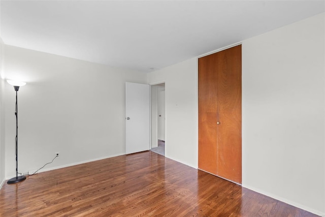 spare room with baseboards and wood finished floors