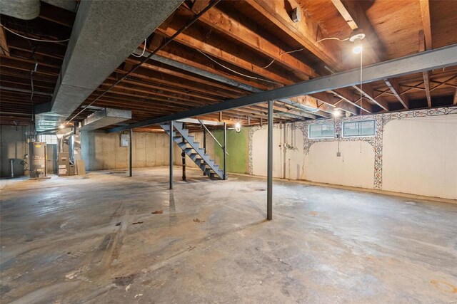 below grade area featuring heating unit, stairway, and gas water heater