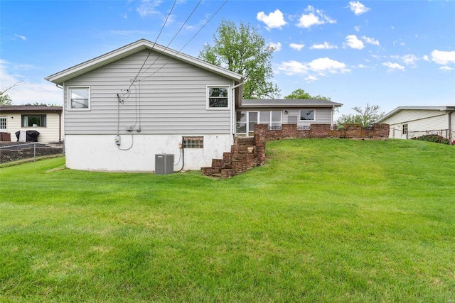 rear view of house with a yard, fence, and central AC unit