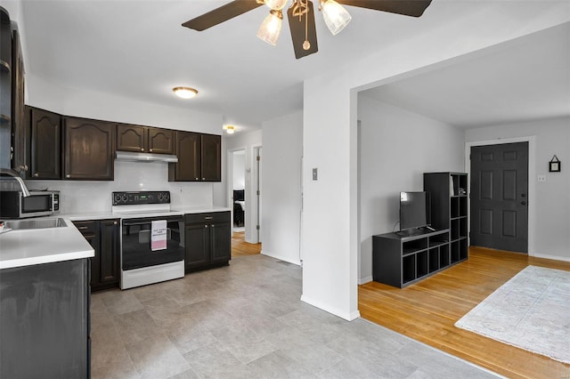 kitchen with a ceiling fan, electric range, a sink, light countertops, and under cabinet range hood