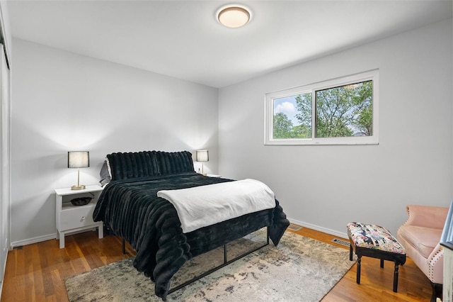 bedroom featuring baseboards, wood finished floors, and visible vents