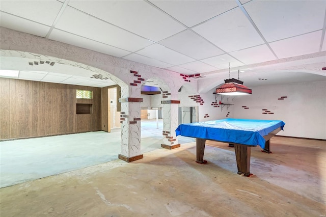 playroom featuring arched walkways, billiards, unfinished concrete flooring, and a paneled ceiling