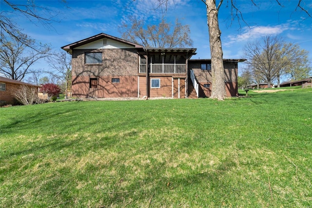 rear view of house with a yard, stairway, and a sunroom