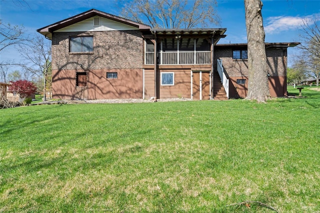 rear view of property featuring stairs, a sunroom, and a lawn
