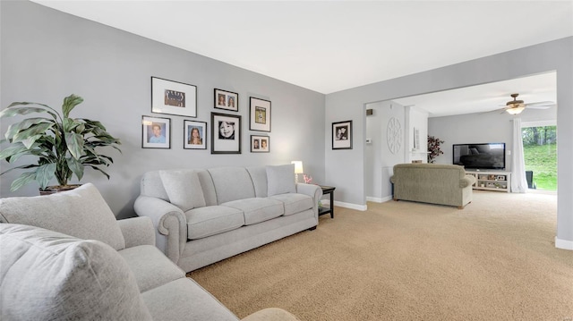 carpeted living area featuring baseboards and a ceiling fan
