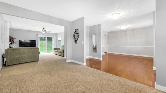 living room featuring baseboards, a ceiling fan, and wood finished floors