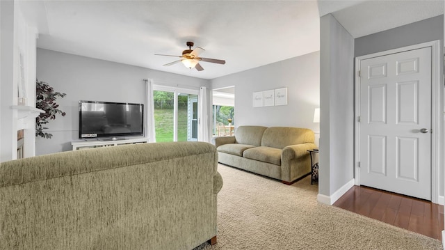 living area featuring wood finished floors, baseboards, and a ceiling fan
