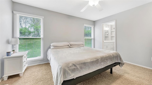 bedroom featuring light carpet, ensuite bath, baseboards, and a ceiling fan