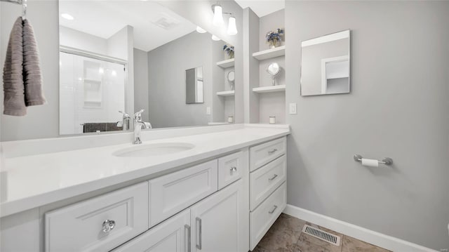 full bath featuring visible vents, baseboards, built in shelves, vanity, and a shower with door