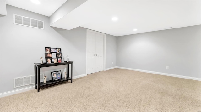 finished basement with visible vents, light colored carpet, and baseboards