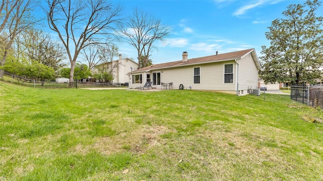 back of house with a fenced backyard, a lawn, a patio, a chimney, and central AC unit