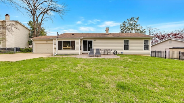 back of house with concrete driveway, a garage, fence, and a lawn