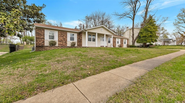 view of front facade featuring brick siding, a front lawn, and fence