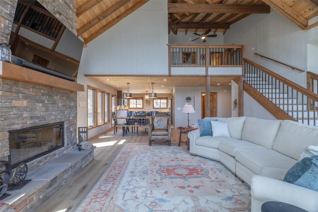 living area with wood finished floors, ceiling fan, a fireplace, and wooden ceiling