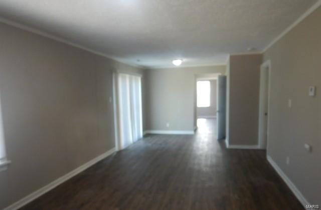 empty room with crown molding, baseboards, and dark wood finished floors