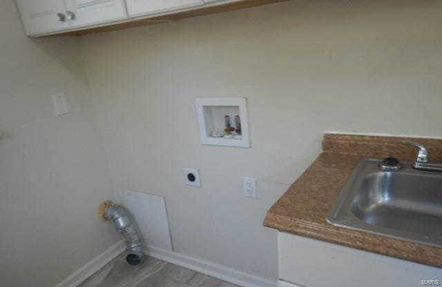 laundry room with baseboards, electric dryer hookup, washer hookup, cabinet space, and a sink