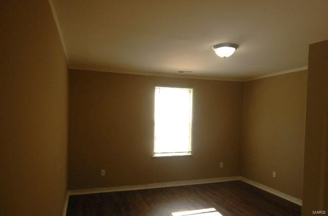 unfurnished room featuring dark wood-style floors, baseboards, and crown molding