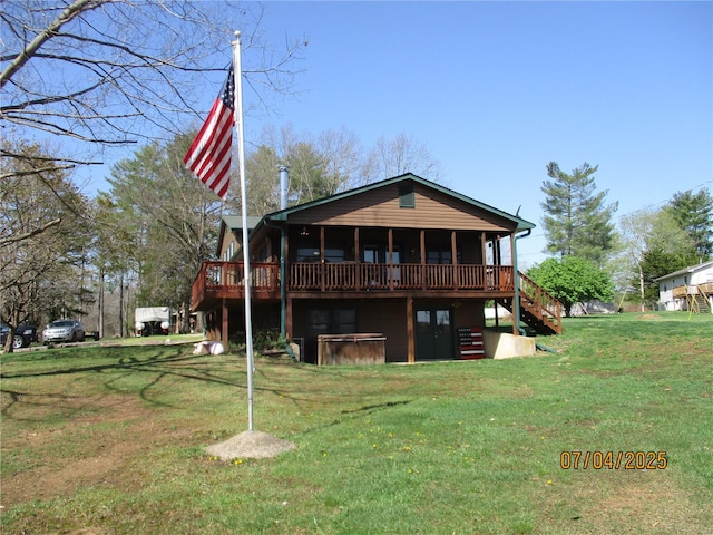 rear view of property featuring stairway, a wooden deck, a lawn, and a hot tub