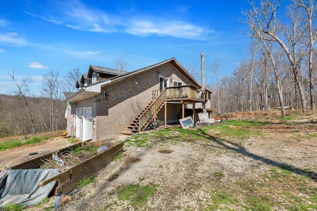 back of property featuring a deck, stairway, and brick siding