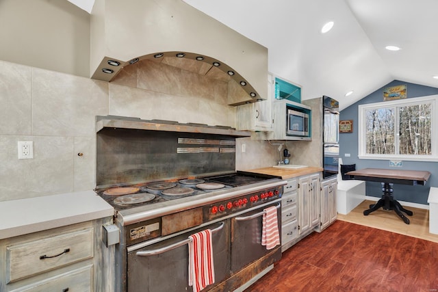 kitchen featuring light countertops, exhaust hood, dark wood-type flooring, decorative backsplash, and stainless steel appliances