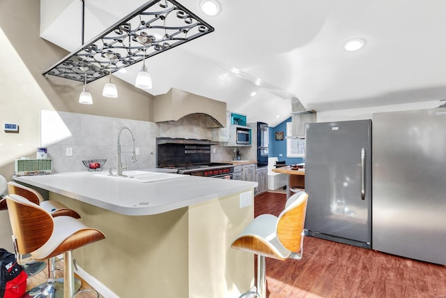 kitchen with tasteful backsplash, premium range hood, lofted ceiling, stainless steel appliances, and wood finished floors