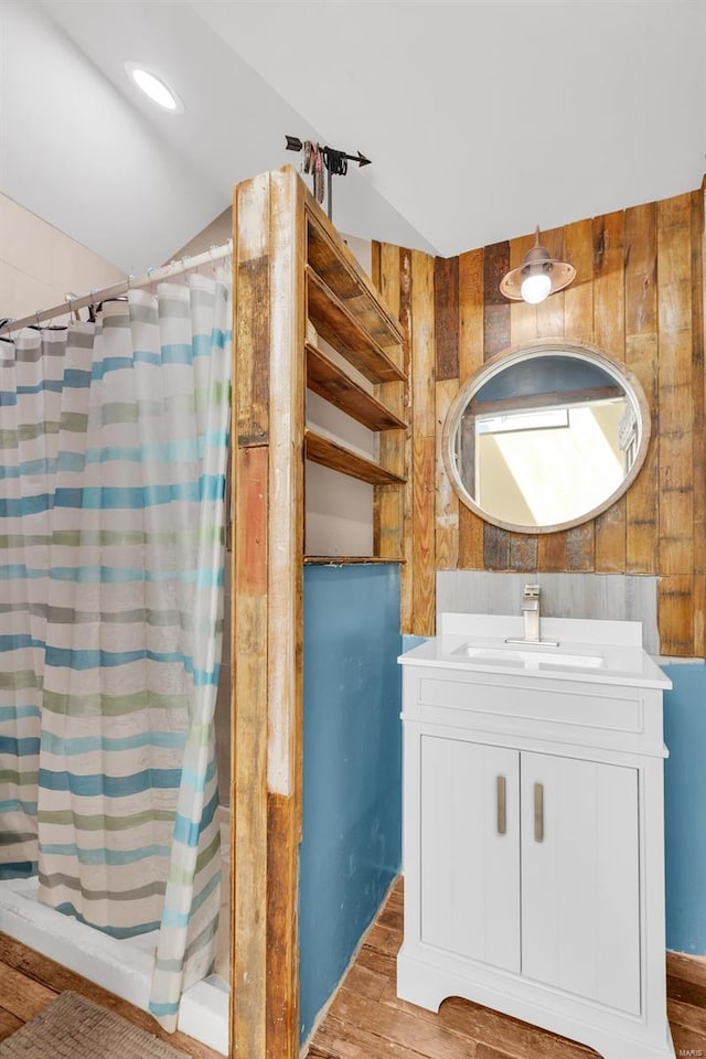 full bathroom featuring wooden walls, vanity, curtained shower, and wood finished floors