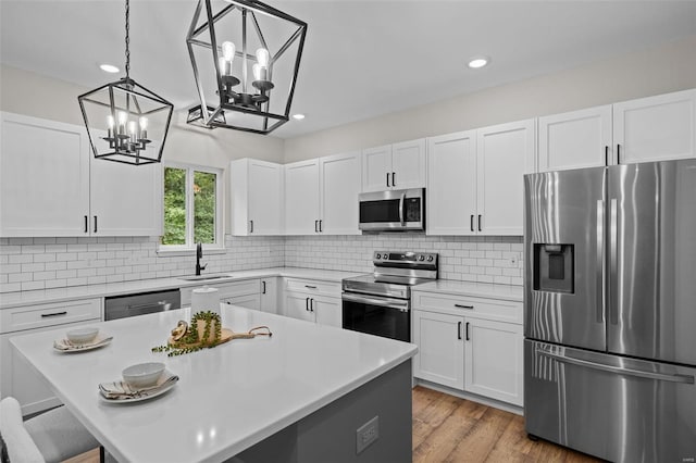 kitchen with decorative backsplash, a notable chandelier, a sink, and appliances with stainless steel finishes