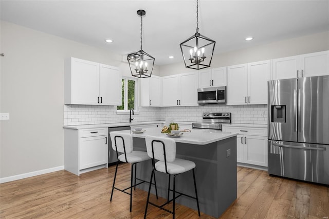 kitchen featuring a breakfast bar, an inviting chandelier, light countertops, light wood-style floors, and appliances with stainless steel finishes