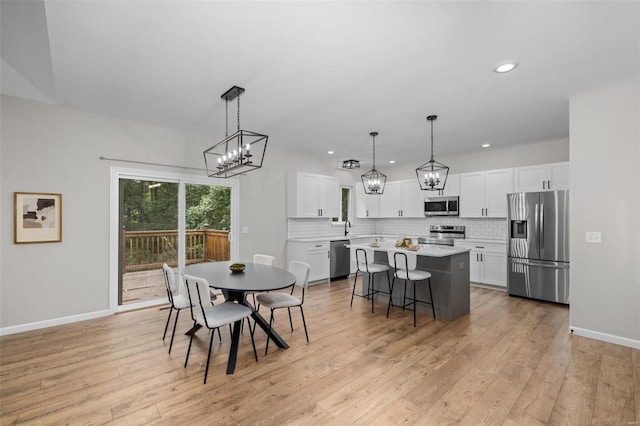 dining room with light wood finished floors, a notable chandelier, and baseboards