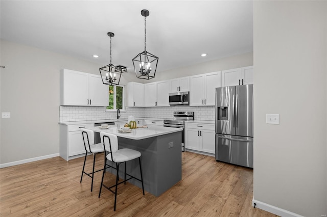 kitchen featuring tasteful backsplash, a notable chandelier, a kitchen breakfast bar, light countertops, and appliances with stainless steel finishes