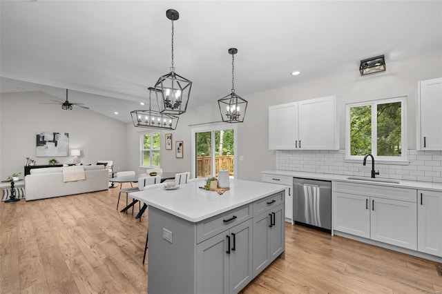 kitchen with light wood-style floors, dishwasher, light countertops, a sink, and decorative backsplash
