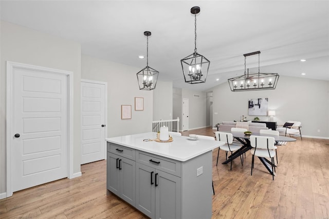 kitchen featuring pendant lighting, light wood-type flooring, a kitchen island, gray cabinets, and lofted ceiling