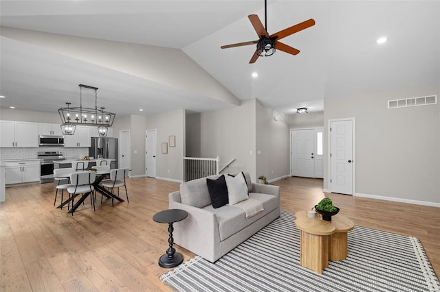 living room featuring light wood-style floors, ceiling fan, baseboards, and visible vents
