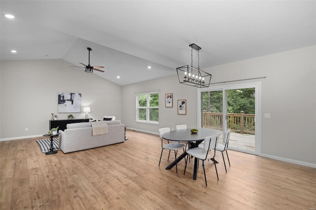 dining room featuring baseboards, light wood-type flooring, vaulted ceiling, and ceiling fan with notable chandelier