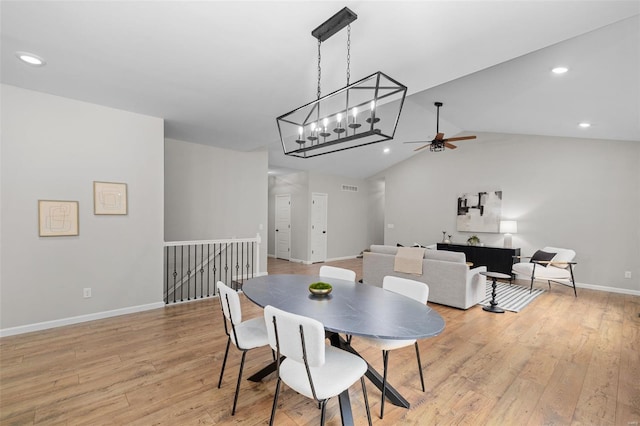 dining area with visible vents, baseboards, a ceiling fan, light wood-style floors, and vaulted ceiling