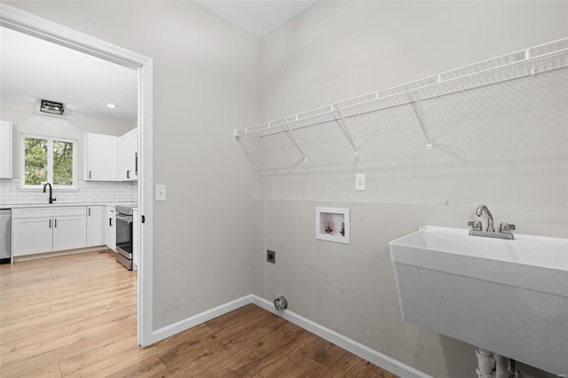 laundry room featuring laundry area, a sink, electric dryer hookup, and light wood-type flooring