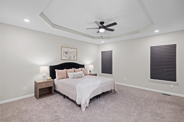 bedroom with visible vents, baseboards, a tray ceiling, recessed lighting, and light colored carpet