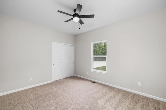 unfurnished bedroom featuring visible vents, baseboards, a closet, ceiling fan, and carpet