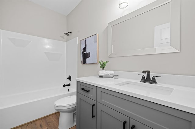 full bath with toilet, vanity, wood finished floors, and  shower combination
