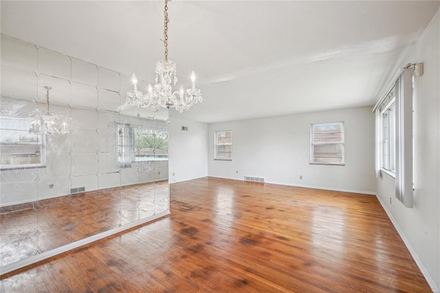 unfurnished room with visible vents, hardwood / wood-style floors, and a chandelier