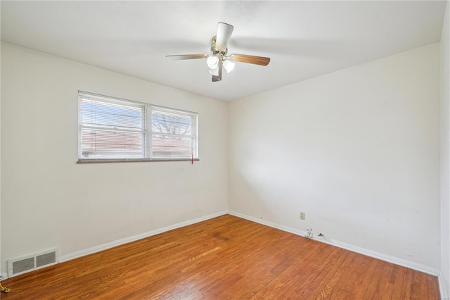 spare room featuring wood finished floors, baseboards, a ceiling fan, and visible vents