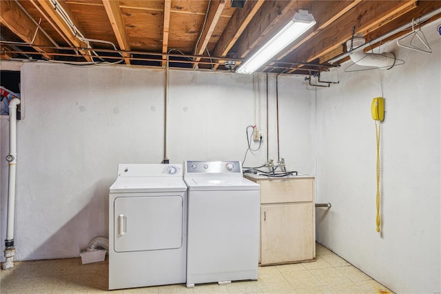 clothes washing area featuring light floors, washer and dryer, and laundry area