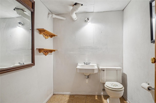 bathroom featuring toilet, a sink, and baseboards