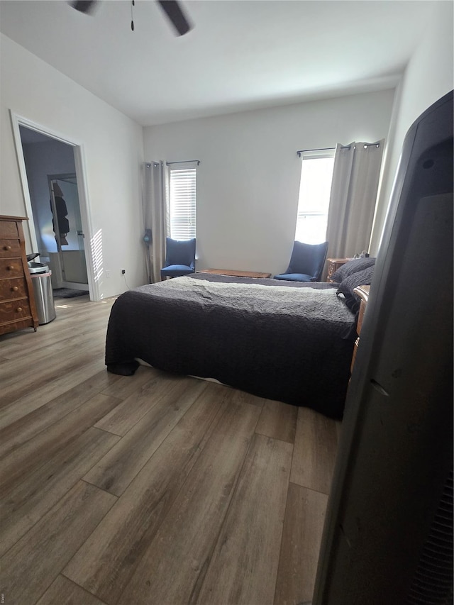 bedroom featuring ceiling fan, multiple windows, and wood finished floors