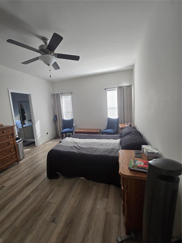bedroom with ceiling fan, multiple windows, and wood finished floors