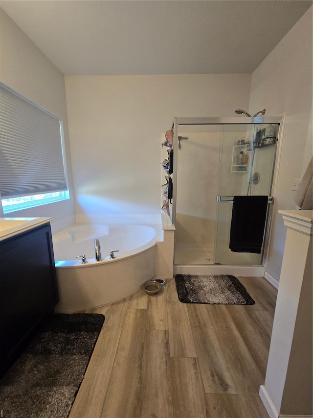 bathroom with a stall shower, wood finished floors, and a garden tub